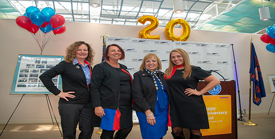 Supervisor Carpenter stands with Southwest Agents by the airport art gallery with large number 20 baloons and celebratory posters behind them.