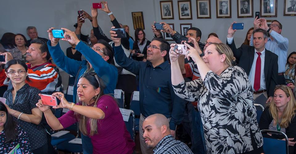 parents stand to take pictures of their child