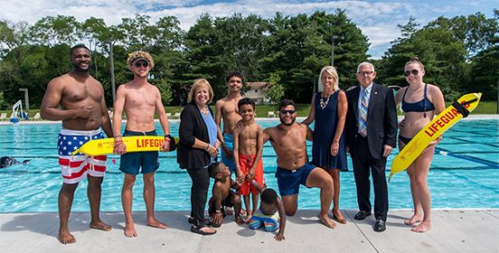 Supervisor Carpenter stands with children, lifeguards and elected officials at the pool safety press conference