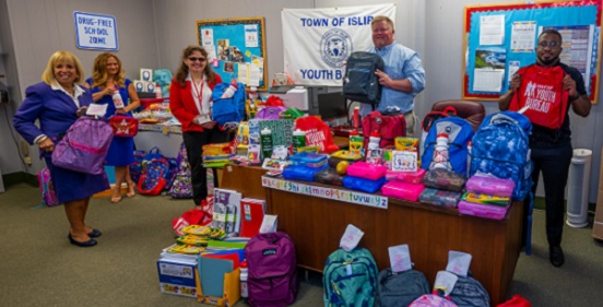 supervisor carpenter and members of the Islip Town Youth Bureau display the many school supplies donated by businesses and members within the community for families in need in the Town