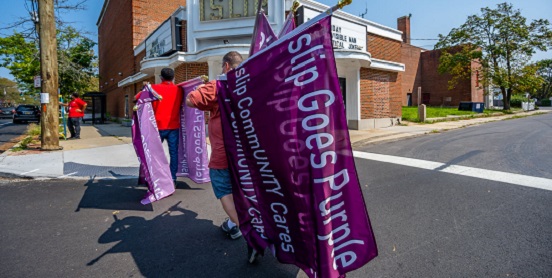 Members of the community and Youth Enrichment Services carry purple Islip Goes Purple flags that they will hang along the main roadways in Islip