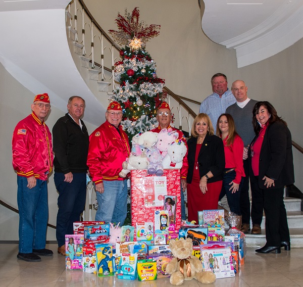 Supervisor Carpenter, Councilman Cochrane and Youth Bureau Director stand in front of a christmas tree surrounded by toys donated by local marines