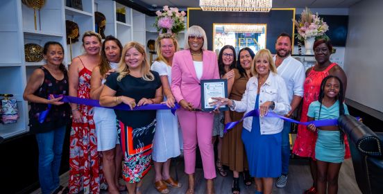 Supervisor, local officials, owner and family gather in boutique with ribbon for cutting ceremony