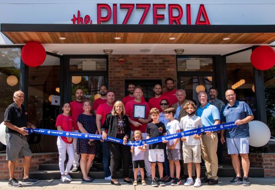 group with ribbon in front of pizzeria