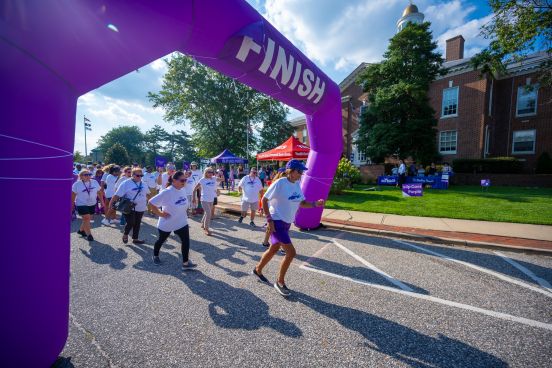 Runners jump off the soon to be finish line with purple fanfare in the scene