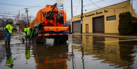 An image of 2 town DPW members and the pump truck working to address a flooded roadway.