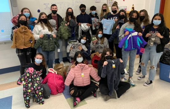 students in group photo holding up donatyed coats