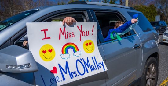 a car with sign hanging out the window expressing admiration for students