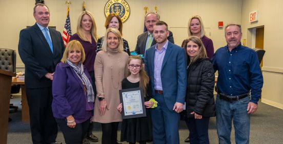 Supervisor Carpenter and the Islip Town Board stand with Ava in the Town Board, having just awarded her for her efforts.