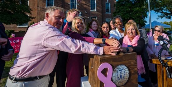 Town Supervisor Angie Carpenter, members of the Islip Town Board place their hands on the lever ready to light the coupola above town hall pink for the month of October.