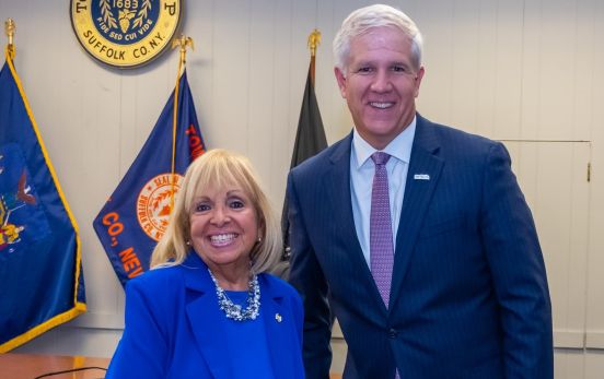 Supervisor and Edward Bonahue pose for a photo infront of the Town Seal in the Islip Town Board Room.