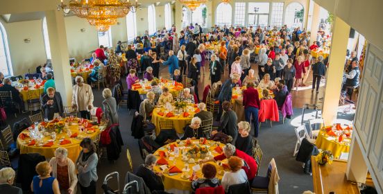 A top-down shot of the ball, with tables filled with dining attendants and the dance floor bustling with partyers. 