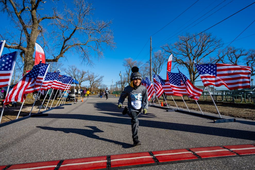 youth boy crosses finish lines with USA flags all around