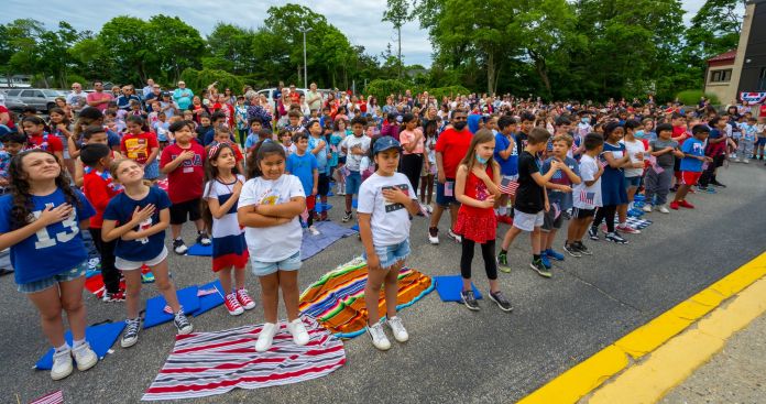 students en mass hold hands over heart for the pledge of allegiance