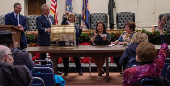 Supervisor Carpenter calls the name of a winner whose hand is up and raised in the foreground of the photo.