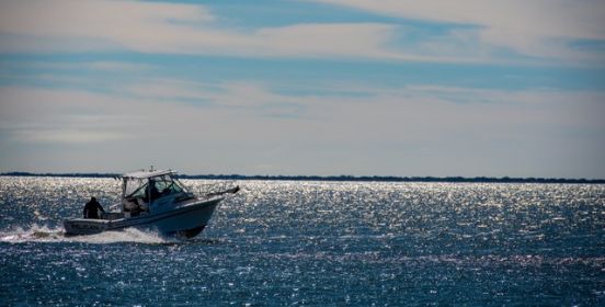 Boat on glistening water rides off into distance