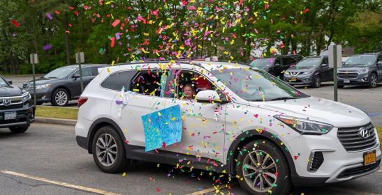  Confetti rises into the air having been thrown by one elementary student partaking in the motorcade. 