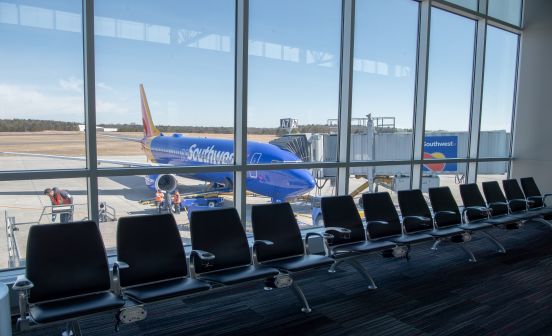An image of a row of seats in front of terminal glass, a southwest airplane at the terminal on the other side.