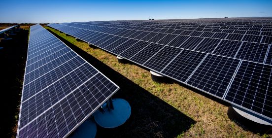 Solar pannels in the foreground cascading into the vanishing point of the horizon, clear blue skies above.