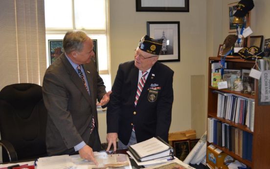 Councilman Cochrane reviewing journal at desk with Veteran