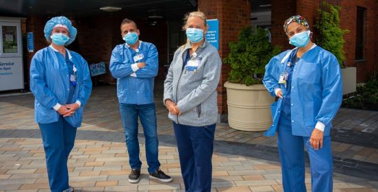 4 Nurses in PPE post in front of hospital