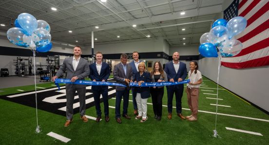 Group photo with ribbon cutting inside facility