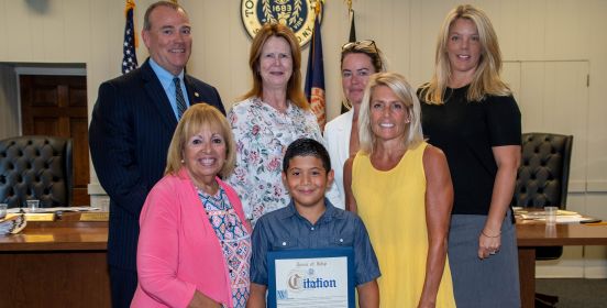 Islip Town Supervisor and the Islip Town Board, pose for a photo with Oliver and his Citation of Recognition in the Town Board Room infront of the Islip Town Seal.