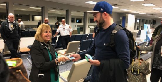 Town Supervisor Angie Carpenter hands a passenger his boarding pass