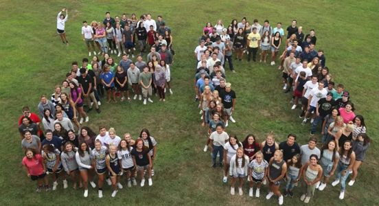 Students in pre-pandemic times form the letter 20 by grouping together