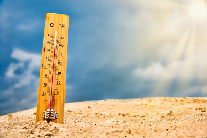 Summer Heat Rising Thermometer in sand with red rising