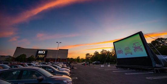 The sun sets in brilliant hues as cars lined up in rows watch the movie