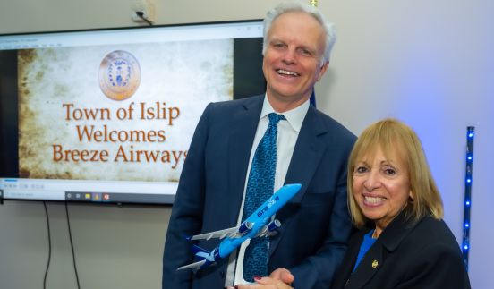 supervisor with Neeleman in front of welcome sign holding model breeze airplane