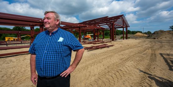 DEC Commissioner Bellew infront of frame of the new structure.