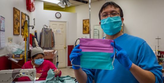 owner holds up created masks as they are being made behind him