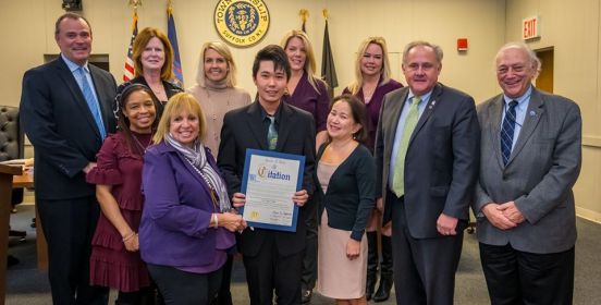 Supervisor Carpenter and the Islip Town Board pose for a photo with Kevin and his family, honoring him for his historic academic achievements.