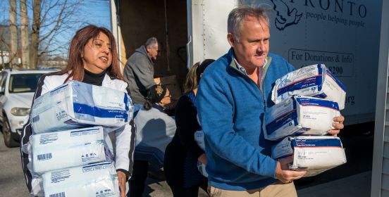 Councilman Cochrane and Maidaya Maldonado carry in stacks of supplies as they are unloaded from the truck.