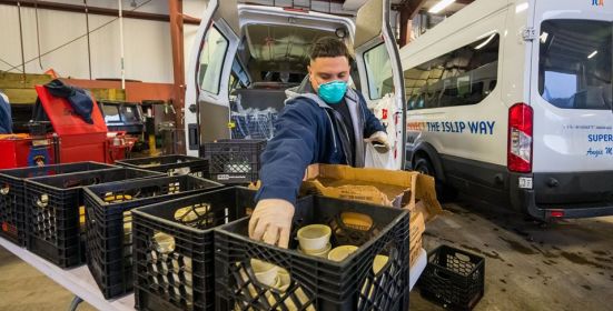 Islip worker in mask stocks crate full of food