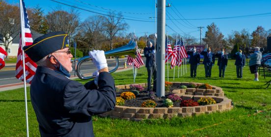 trumpet in forground while flag is raised to salutes behind it