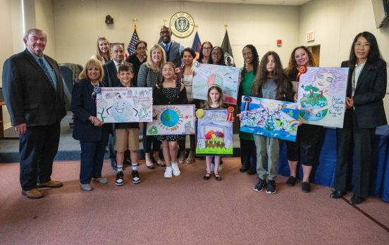 Students in group photo with Supervisor holding up their artwork