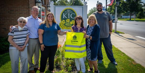 Supervisor with group holds up new KIC vest