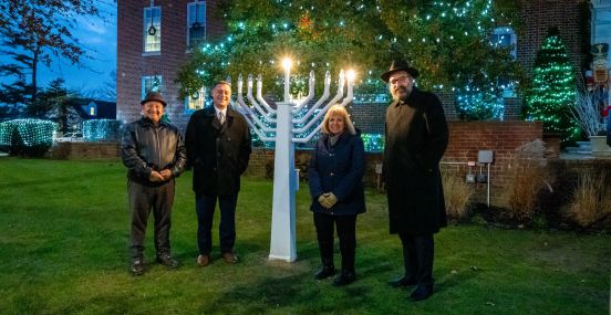 local officials standing next to lit menorah