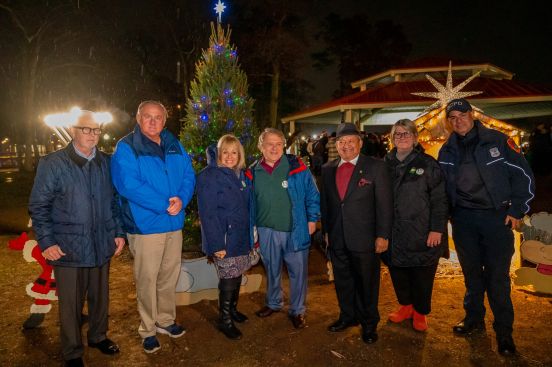 Group photo of local officials with lit tree in background