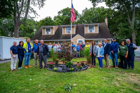 group shot surrounding the beautified landscaping, american flag on a pole center frame