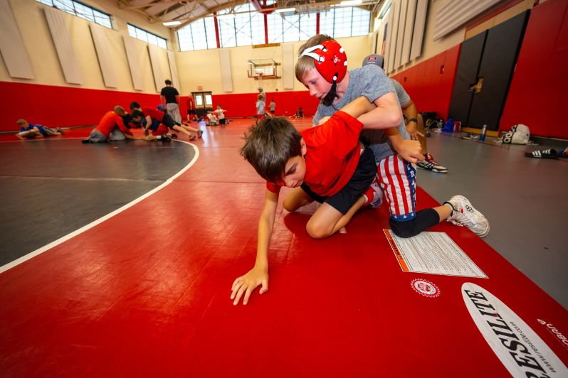 as wrestlers pair off, one wrestler tries to escape starting position from mat