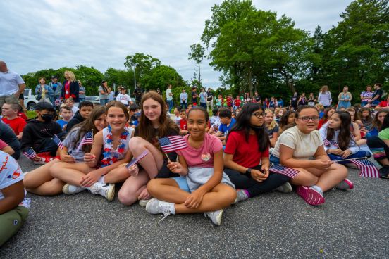 students in red white and blue sitting in group take photo