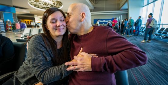 Ryamond hold's Ashley's hand over his and her father's heart while kissing her on the cheek, here eyes closed and smiling.